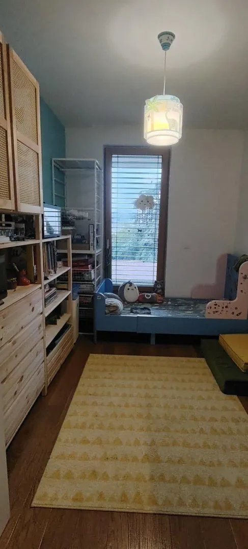 Children's bedroom with a bed, wooden cabinets, and a window.