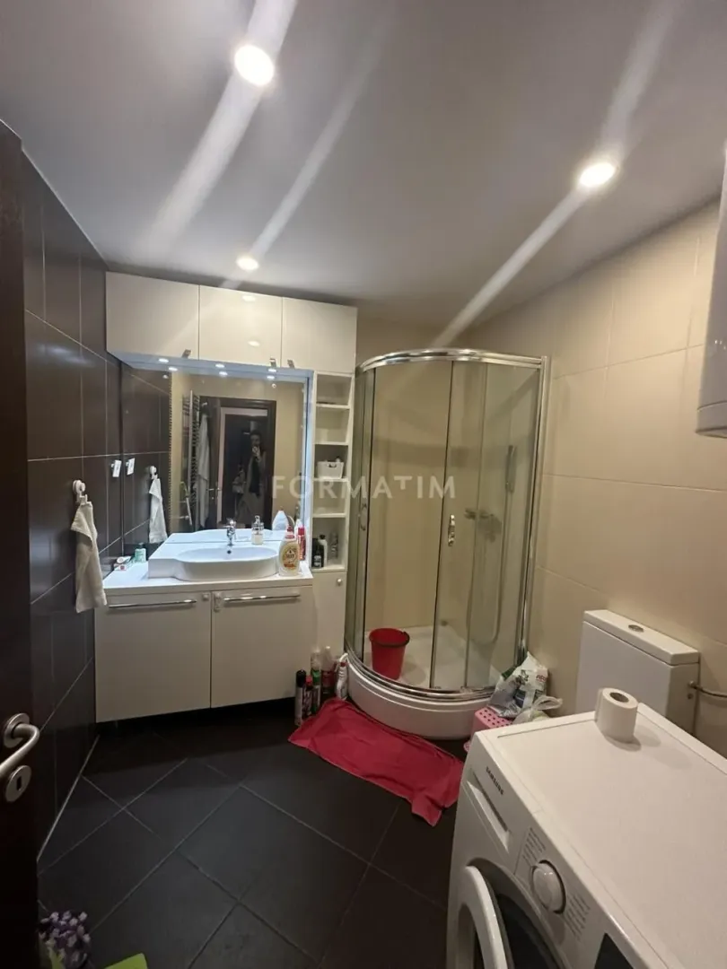 Bathroom equipped with a washbasin, shower cabin, toilet, and washing machine.