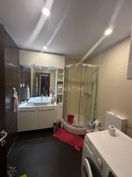 Bathroom equipped with a washbasin, shower cabin, toilet, and washing machine. - image 13