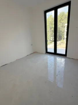 Prazna soba sa svijetlim pločicama na podu i velikim prozorom. - image 4