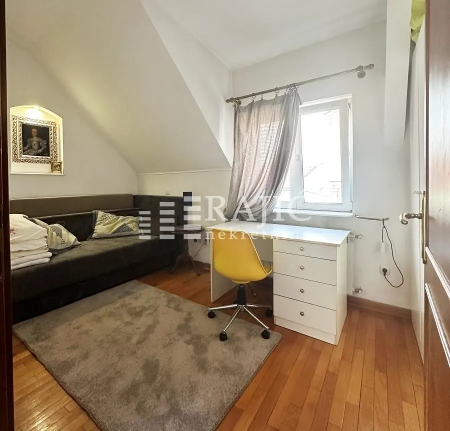 Smaller room with a bed, desk, and rug.