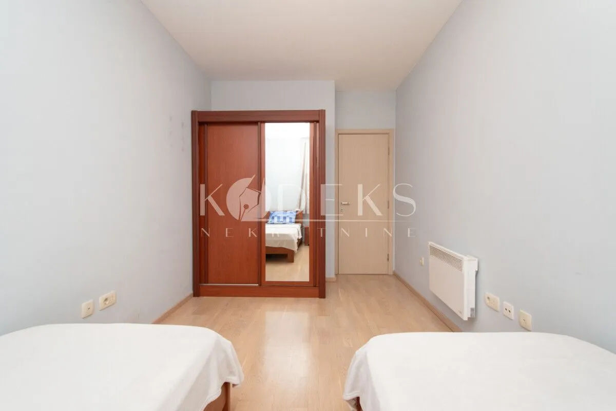 Bedroom with two beds, wooden wardrobe with mirror, and laminate flooring.