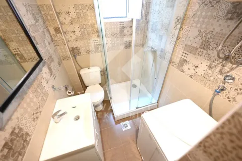 Compact bathroom with a shower cabin, washbasin, toilet, and washing machine. - image 5