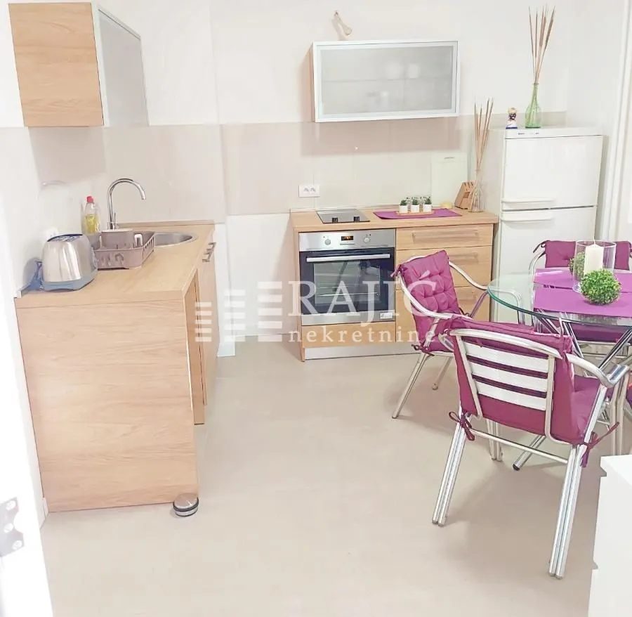 Small kitchen with a dining table and purple chairs.