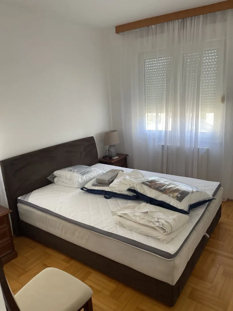 Bright bedroom with a double bed and parquet floor.