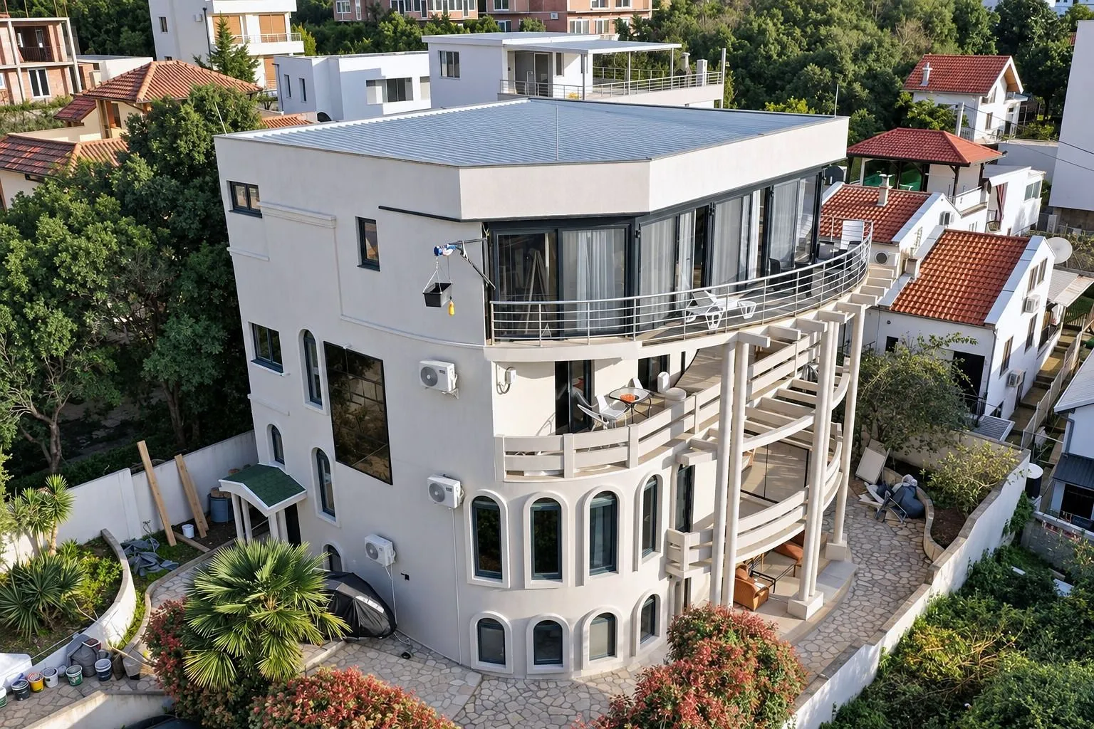 Pogled iz vazduha na modernu višespratnu kuću sa terasama i dvorištem.