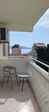 Manji namješteni balkon sa stolom, stolicom i pogledom na more. - image 2