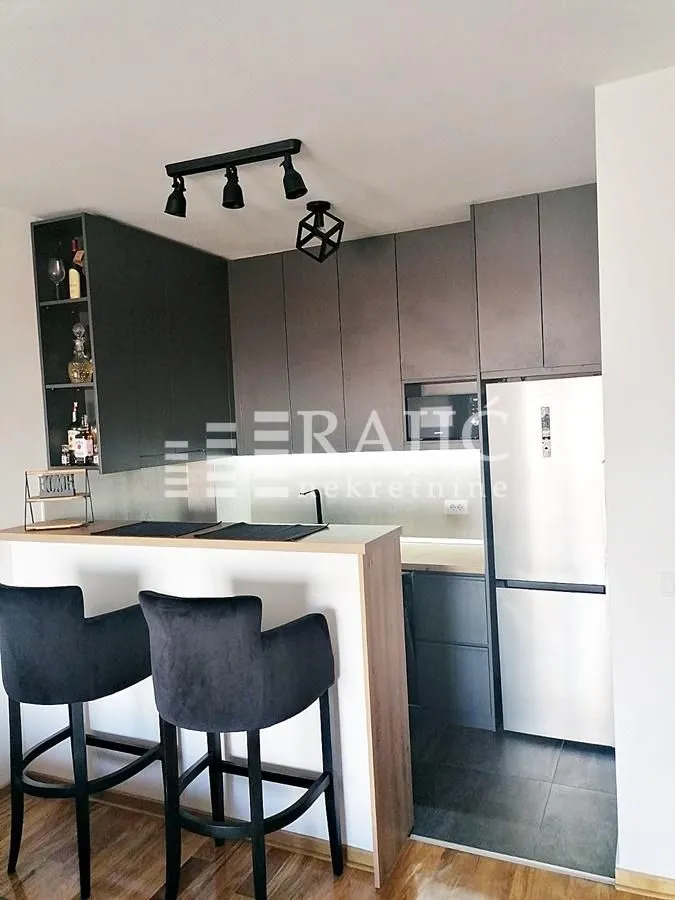 Modern kitchen with a bar counter and dark cabinetry.