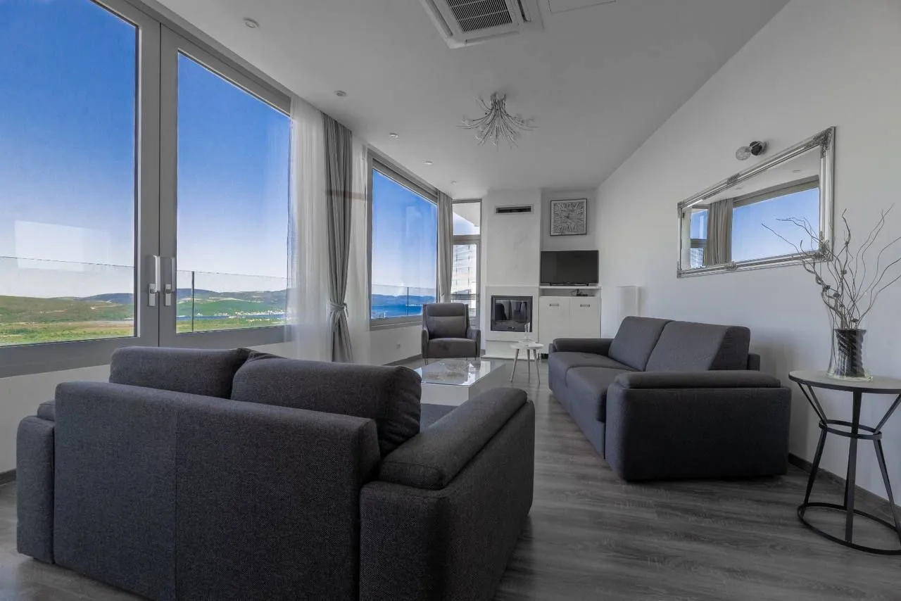 Spacious living room with seating furniture and large windows offering a sea view.