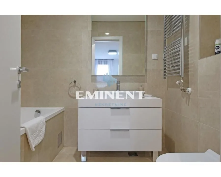 Modern bathroom with a vanity, mirror, and tiled bathtub.