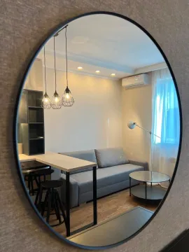 Living room with a sofa, a bar counter, and a wall mirror. - image 7