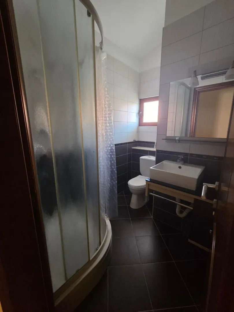 Manje opremljeno kupatilo sa tuš kabinom, umivaonikom i wc šoljom.
