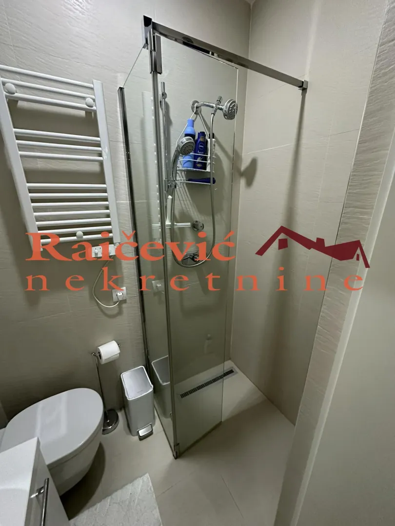Manje kupatilo sa tuš kabinom i WC šoljom.
