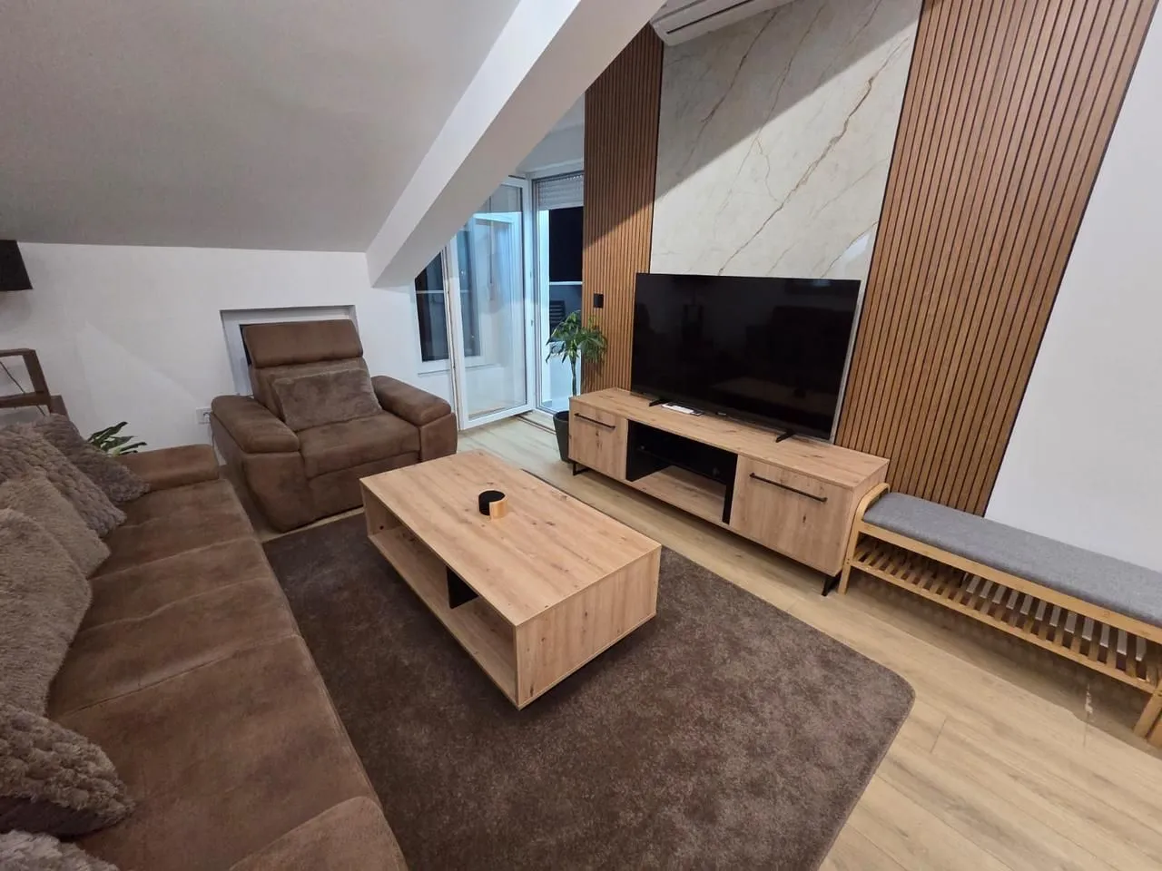 Living room with a sofa, TV, and wooden wall panels.