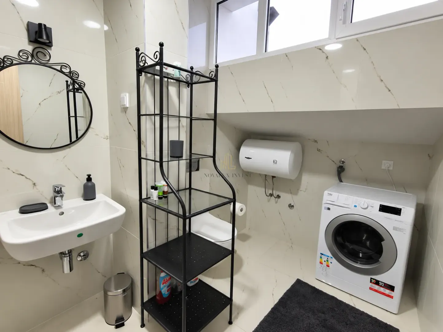 Bathroom equipped with a sink, washing machine, water heater, and a black metal shelving unit.