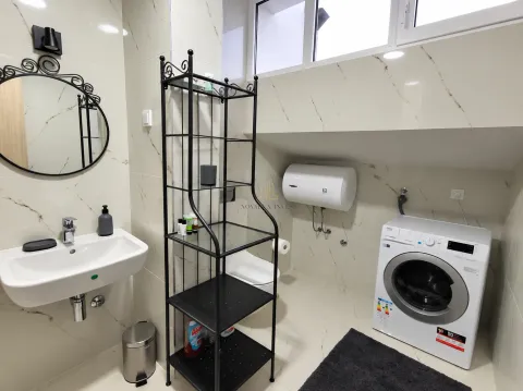 Bathroom equipped with a sink, washing machine, water heater, and a black metal shelving unit. - image 9