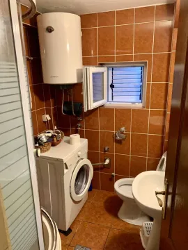 Small bathroom with a washing machine, water heater, and brown tiles. - image 15