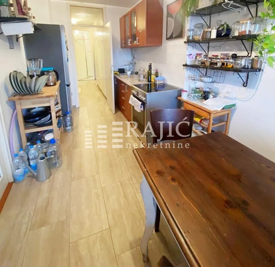 Long kitchen with a dining table and wooden cabinets.