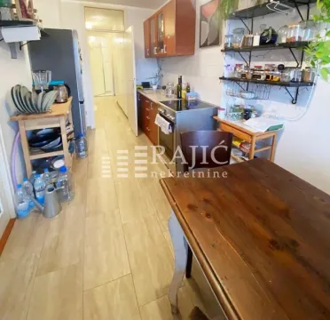 Long kitchen with a dining table and wooden cabinets. - image 6