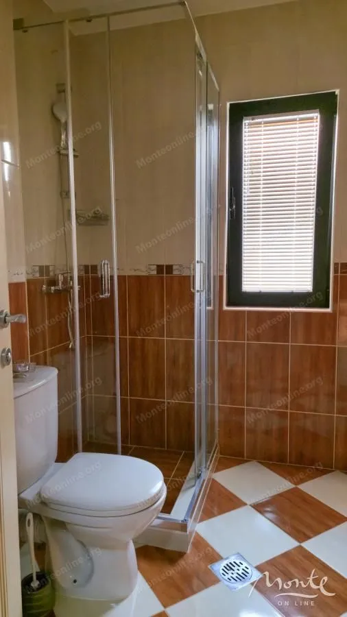 Kupatilo sa tuš kabinom, WC šoljom i prozorom.