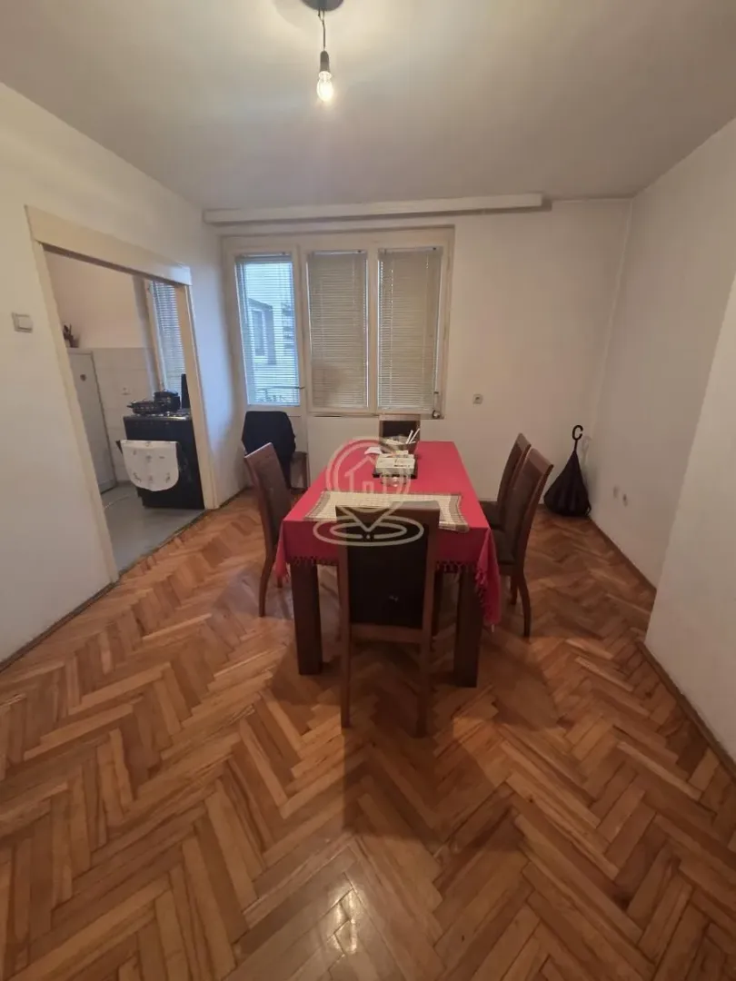 Trpezarija sa stolom, stolicama i parketom na podu.