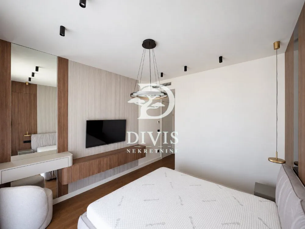 Modern bedroom with a double bed, TV, and a mirror.