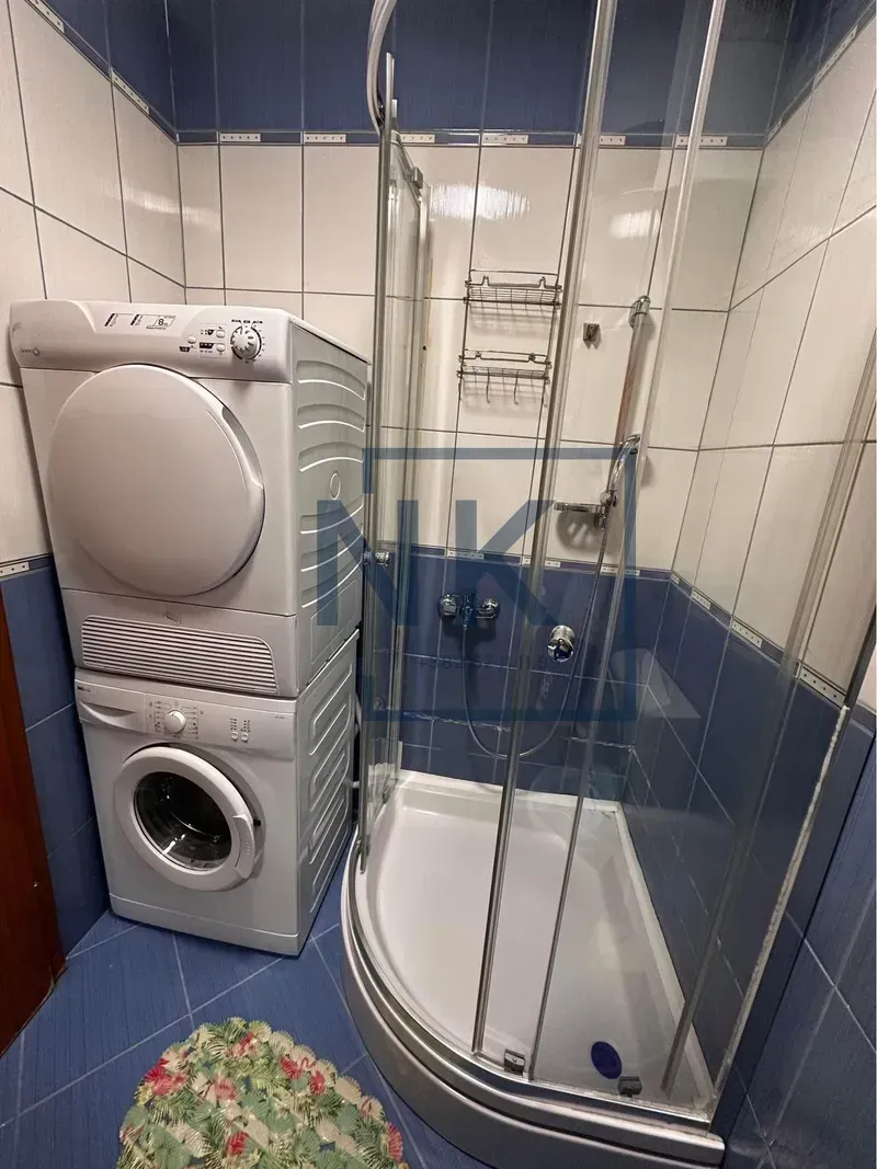 Kupatilo sa tuš kabinom i mašinama za pranje i sušenje veša.