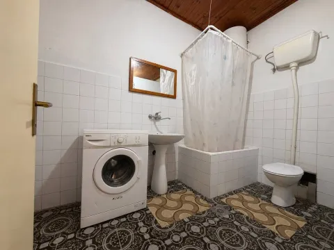 Starije opremljeno kupatilo sa kadom, umivaonikom i veš mašinom. - image 9