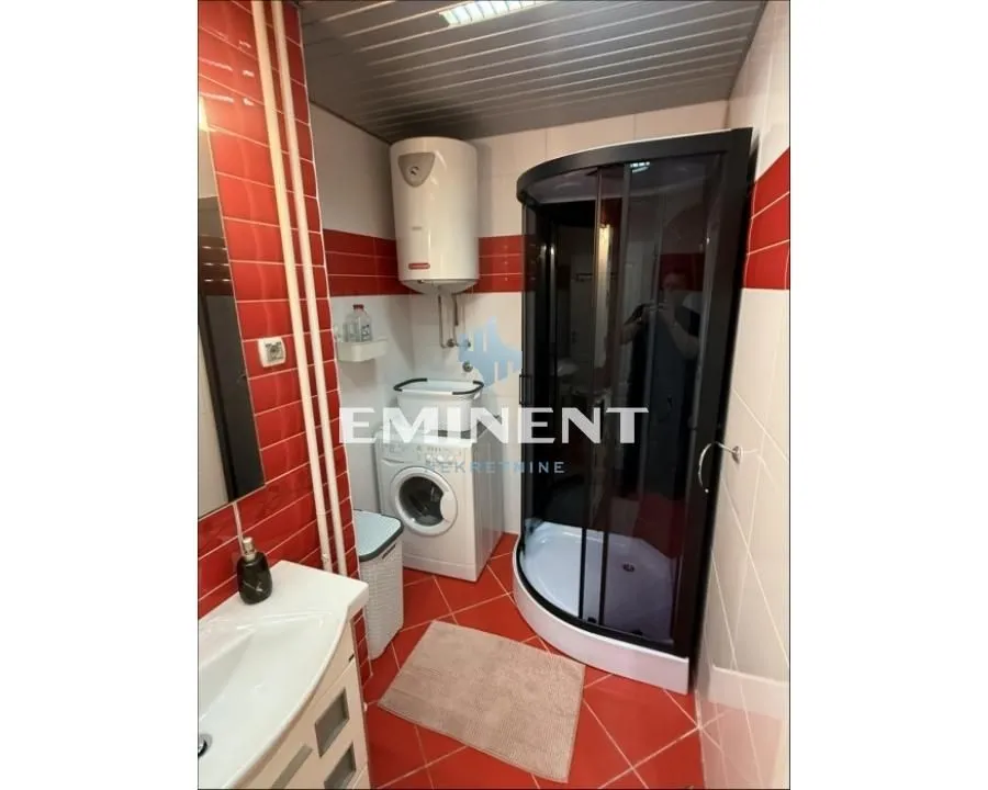 Bathroom with a shower cabin, washbasin, washing machine, and water heater.