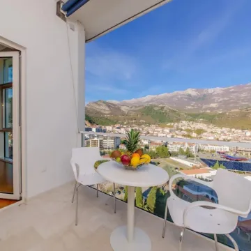 Covered balcony with seating set and city and mountain views. - image 2