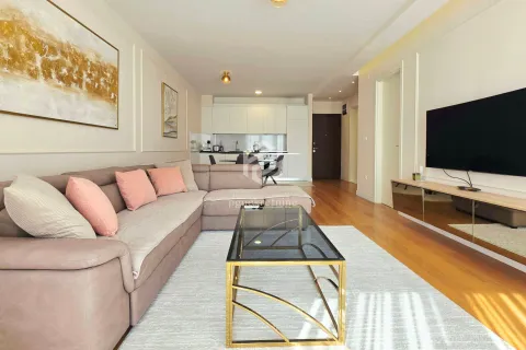 Living room with a sofa, coffee table, and TV, overlooking the kitchen in the background. - image 5