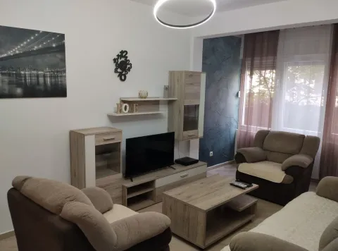 Svijetla dnevna soba sa udobnim namještajem, televizorom i drvenim stolom. - image 23