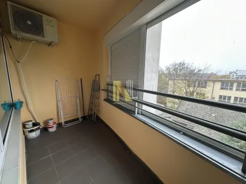 Zastakljeni balkon sa klima uređajem i pogledom na okolne zgrade. - image 10
