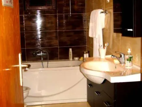 Kupatilo sa kadom, lavaboom i tamnim zidnim pločicama. - image 12