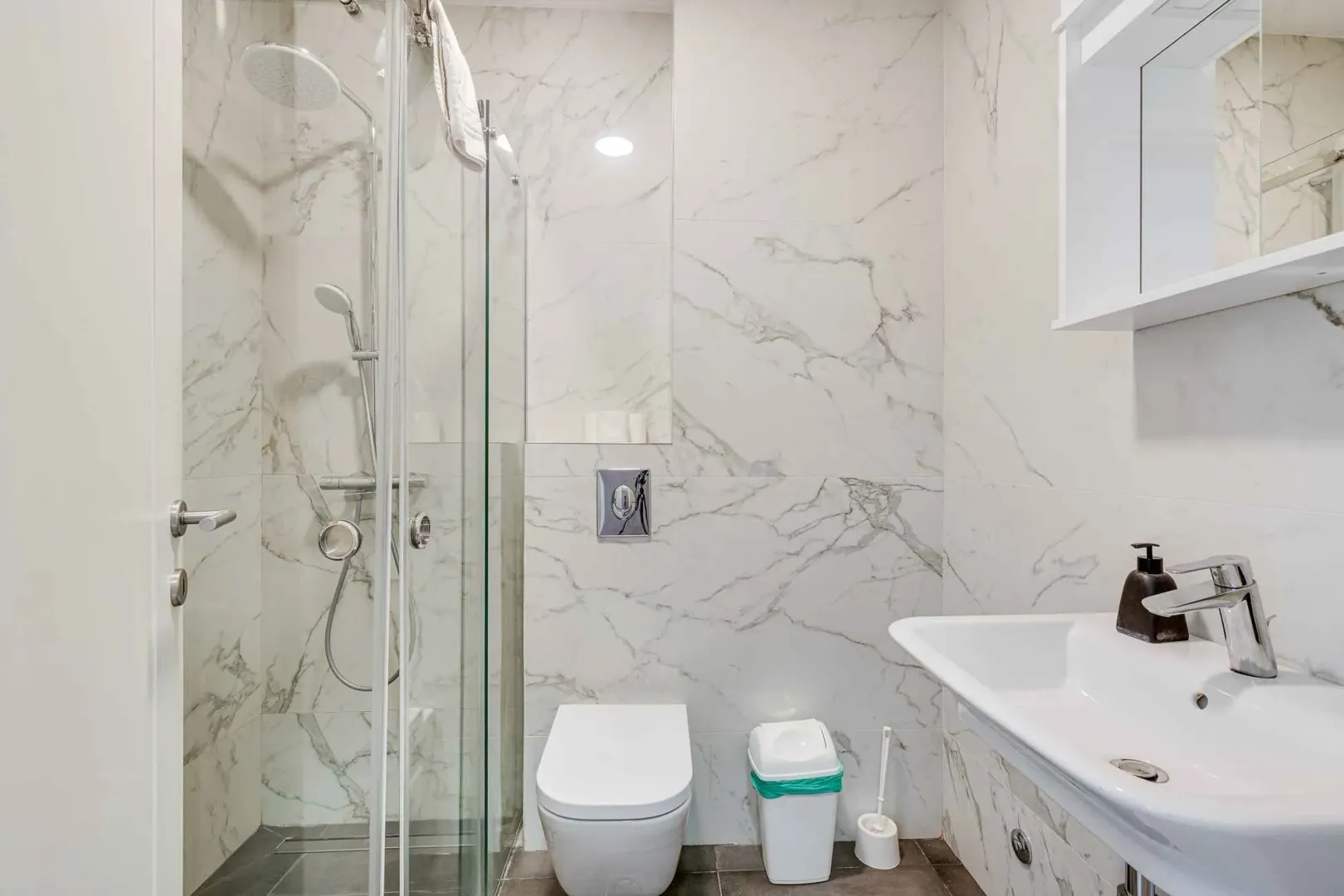 Modernly equipped bathroom with a walk-in shower and marble-effect tiles.