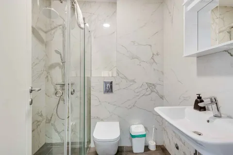 Modernly equipped bathroom with a walk-in shower and marble-effect tiles. - image 20
