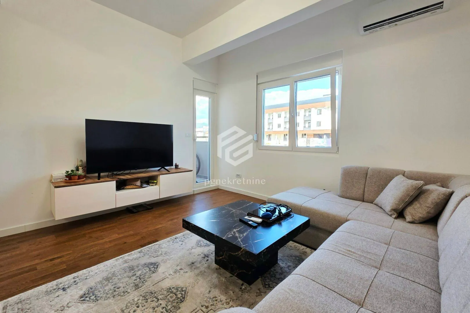 Living room with a sectional sofa, TV, and access to the terrace.