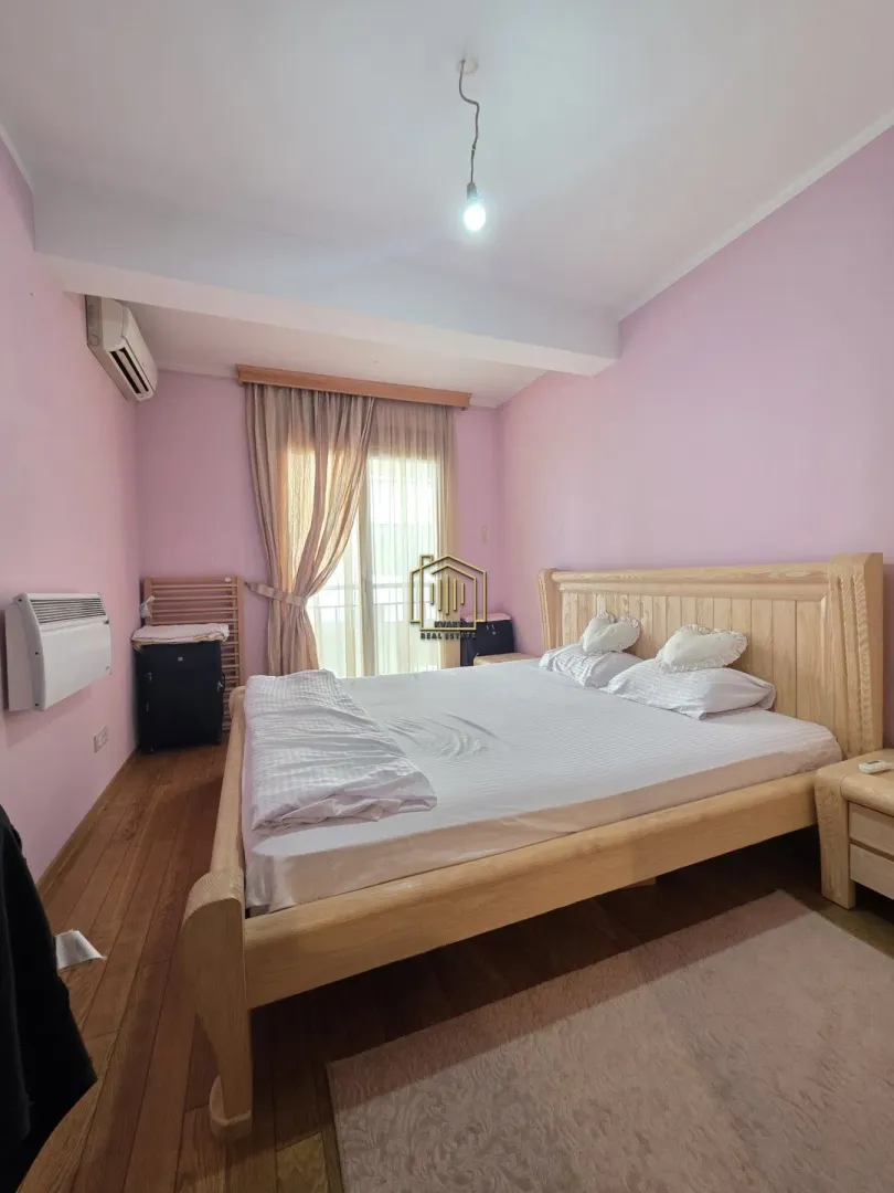 Spavaća soba sa velikim drvenim krevetom i roze zidovima.