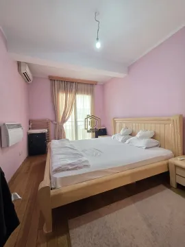 Spavaća soba sa velikim drvenim krevetom i roze zidovima. - image 9