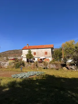 Pogled na stariju kuću sa crvenim krovom i okućnicom. - image 3