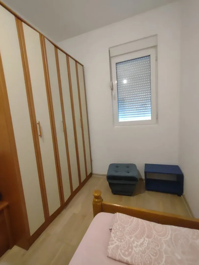Manja spavaća soba sa velikim ugradnim garderoberom, krevetom i prozorom.