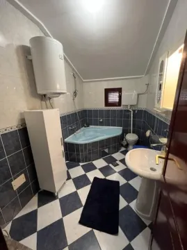 A bathroom with blue and white tiles, a corner bathtub, and a water heater. - image 22