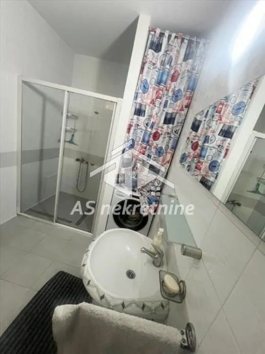Bathroom with a washbasin, shower cabin, and washing machine.