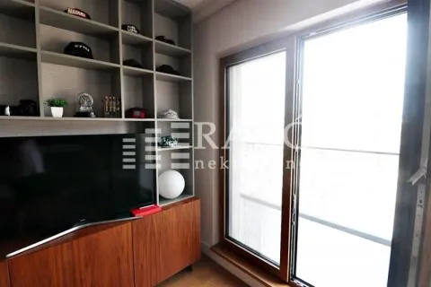 Living room with built-in shelving, TV, and a large window. - image 9
