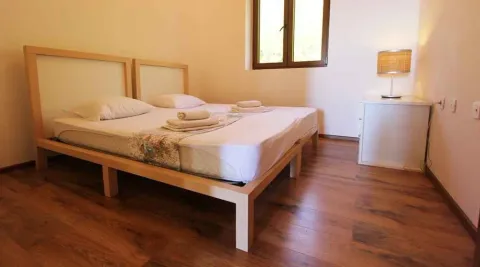 Svijetla spavaća soba sa dva spojena drvena kreveta i noćnim ormarićem. - image 5