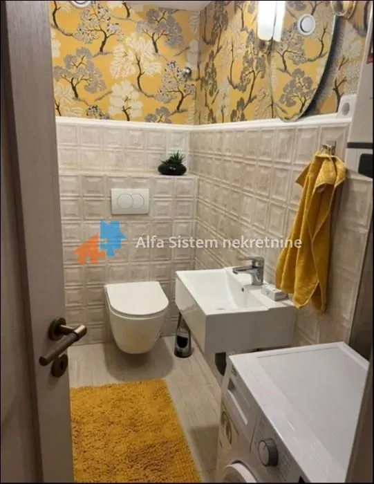 Small bathroom with a toilet, washbasin, washing machine, and yellow wallpaper.