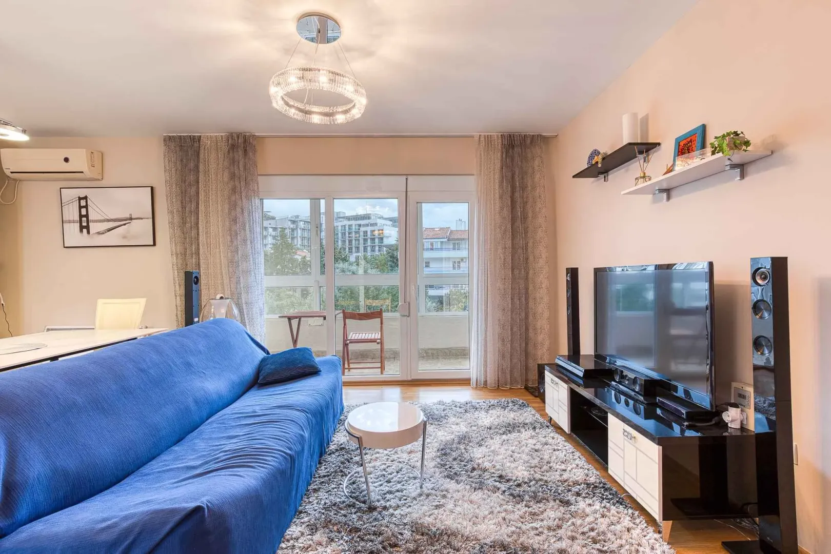 Living room with a blue sofa, TV, and access to the terrace.