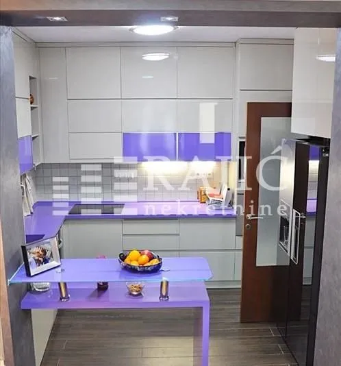 Modern kitchen with light cabinetry and purple details.