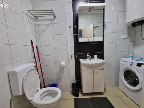 Kupatilo opremljeno sanitarijama, umivaonikom, veš mašinom i bijelim pločicama. - image 20