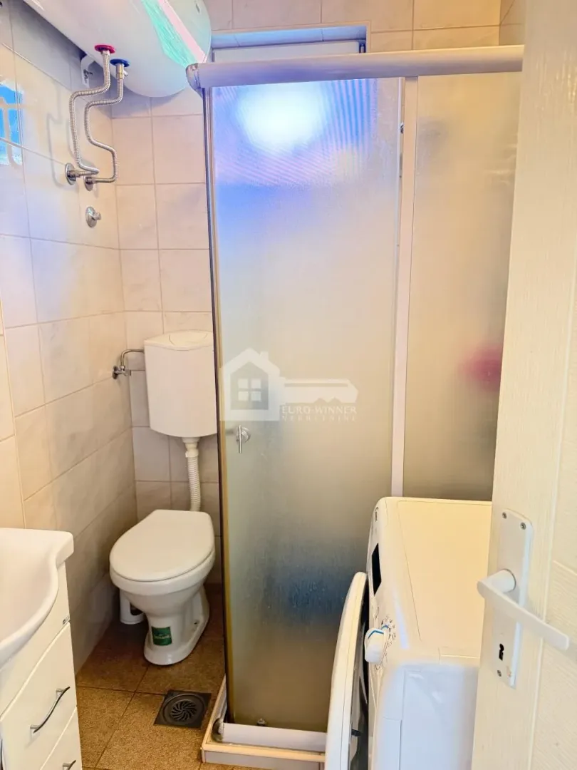 Kompaktno kupatilo sa tuš kabinom, WC šoljom i veš mašinom.